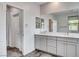 Bathroom with a gray double vanity, large mirror, and window with custom shades at 361 Cooper Hawk Ct, Las Vegas, NV 89138