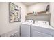 Well-lit laundry room with white washer and dryer and ample storage on a shelf above at 7935 Pandora Sky St # 381, North Las Vegas, NV 89084