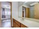 Bathroom vanity with wood cabinets, single sink, and view to bedroom at 875 Rhinegold Way, Las Vegas, NV 89110