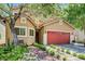Charming home with a red garage door and lush front yard landscaping with trees and stone pathway at 9370 Corkfish St, Las Vegas, NV 89178