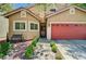Beautiful home boasts a red garage door, mature trees, and meticulously maintained desert landscaping at 9370 Corkfish St, Las Vegas, NV 89178