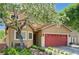 Beautiful home featuring a red garage door, mature trees, and meticulously maintained landscaping at 9370 Corkfish St, Las Vegas, NV 89178