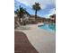 Community pool featuring blue water, lounge chairs, palm trees, and fenced perimeter at 1320 Driscoll Dr # 202, Las Vegas, NV 89128