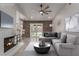 Staged living room with fireplace, ceiling fan, gray sectional couch, and access to backyard at 1816 Mazzanti Way, Henderson, NV 89014