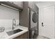 This laundry room features a stackable washer and dryer, sleek cabinets, and a stainless steel sink at 2240 Boutique Ave, Henderson, NV 89044