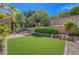 Secluded backyard featuring artificial turf, rock accents, and mature trees creating a peaceful outdoor oasis at 2805 Hanging Rock Dr, Las Vegas, NV 89134