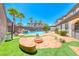 Beautiful backyard with a custom pool, built-in firepit with seating, palm trees, and lush artificial grass at 2820 Sisteron Ct, Henderson, NV 89044