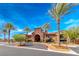 Beautiful clubhouse exterior with arched entryway, terracotta roof, and mature palm trees under a blue sky at 2820 Sisteron Ct, Henderson, NV 89044