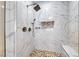 Modern walk-in shower with marble-style tile, river rock flooring, and a built-in bench at 2820 Sisteron Ct, Henderson, NV 89044
