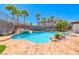 Resort-style pool with a rock waterfall, spa, and ample patio space surrounded by lush palm trees at 2820 Sisteron Ct, Henderson, NV 89044