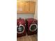 A laundry room featuring a modern red washer and dryer, complemented by wooden cabinets for storage at 3750 Morning Canyon St, Las Vegas, NV 89147