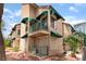 A tan two-story condo building with green awnings and private balconies, complemented by palm trees at 440 Elm Dr # 103, Las Vegas, NV 89169
