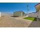 Wide backyard features stone ground cover, a storage shed, artificial turf, and a patio with an umbrella at 445 Concord Way, Henderson, NV 89015