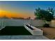 A backyard featuring a landscaped design including a planter, artificial turf, tree, and stone ground cover at dusk at 445 Concord Way, Henderson, NV 89015