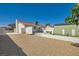 Spacious backyard area with stone ground cover, a storage shed, white perimeter wall, and a patio with an umbrella at 445 Concord Way, Henderson, NV 89015