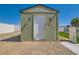 Exterior shot of the storage shed with a white door, outdoor lights, stone ground cover, and artificial turf at 445 Concord Way, Henderson, NV 89015