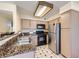 Close-up of kitchen with granite counters, stainless steel refrigerator, and black appliances at 5241 Caspian Springs Dr # 203, Las Vegas, NV 89120
