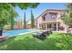 A backyard with a pool, lounge chairs, covered patio with outdoor kitchen at 529 Caribbean Palm Dr, Las Vegas, NV 89138