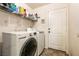 Functional laundry room features a modern washer and dryer with storage shelving and a door to the outside at 5824 Kane Holly St, Las Vegas, NV 89130