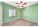 Green bedroom featuring a ceiling fan, window with blinds, and modern wood-look flooring at 5931 Allanche Ave, Las Vegas, NV 89141