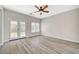Bright, airy bedroom featuring wood-look floors, a ceiling fan, and double doors leading to a patio at 5931 Allanche Ave, Las Vegas, NV 89141