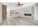 Open concept living room with brick accent wall, electric fireplace and modern kitchen at 5931 Allanche Ave, Las Vegas, NV 89141
