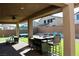 Covered patio with outdoor kitchen, table, and lounge chairs overlooks backyard at 7855 Skyler Falls Ln, North Las Vegas, NV 89084
