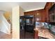 Kitchen with black refrigerator, wooden cabinets, granite countertops, and stairs leading to the second floor at 9073 Spoonbill Ridge Pl, Las Vegas, NV 89143