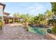 Lush backyard featuring a freeform pool, rock features, shaded patio and outdoor seating areas, perfect for relaxation at 10301 Orkiney Dr, Las Vegas, NV 89144