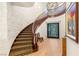 Grand curved staircase with wood railings, stone accent wall, and decorative lighting at 10301 Orkiney Dr, Las Vegas, NV 89144