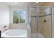 Bathroom featuring a glass-enclosed shower and a soaking tub with tile surround at 11221 Victoria Medici St, Las Vegas, NV 89141