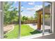 A beautifully landscaped backyard featuring a manicured lawn and patio is viewed through a window at 11847 Corenzio Ave, Las Vegas, NV 89138