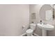 Powder room features pedestal sink, toilet, round mirror and modern decor at 11847 Corenzio Ave, Las Vegas, NV 89138