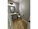 Powder room features wood-look flooring, gray walls, white trim, and a modern vanity with dark hardware at 150 Greenbriar Townhouse Way, Las Vegas, NV 89121