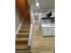 Hallway view with wood-look floors, white cabinets, quartz countertops, and nearby staircase at 150 Greenbriar Townhouse Way, Las Vegas, NV 89121