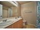 Bathroom features a dual sink vanity with oak cabinets and shower with bright curtain at 1740 Flores Ln, Henderson, NV 89012
