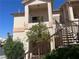 Stucco condo building with a covered balcony, metal stair rails, and mature landscaping at 1830 N Buffalo Dr # 2022, Las Vegas, NV 89128