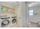 Convenient laundry room with a washer, dryer, shelving, adjacent to the home's bathroom at 1952 W Hammer Ln, North Las Vegas, NV 89031