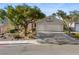 Charming single-story home featuring a well-manicured front yard, mature trees, and a two-car garage on a sunny day at 2158 Shubert Ave, Henderson, NV 89052