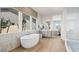 Bright bathroom featuring a soaking tub, large windows, and double vanity with light wood-look flooring at 243 Paraggi Bay Dr, Henderson, NV 89011