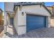 Close-up of a home's exterior featuring a blue garage door and neutral colored siding with a paved stone driveway at 2637 Begonia Falls Ave # 87, North Las Vegas, NV 89081
