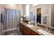 Well-lit bathroom featuring double sinks, granite counters, shower and a large mirror at 3468 Isle Dr, Las Vegas, NV 89141