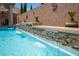 Close up of a gorgeous in-ground pool featuring a tiered stacked stone waterfall feature at 3468 Isle Dr, Las Vegas, NV 89141