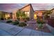 Home exterior featuring desert landscaping, a brick driveway, and warm exterior lighting at 44 Alta Cascata Pl, Henderson, NV 89011