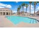 Community pool with clear blue water, surrounded by palm trees and lounge chairs for relaxation at 5000 Red Rock St # 259, Las Vegas, NV 89118