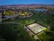 Dusk aerial view of community tennis courts and walking paths surrounded by mature trees in a well-kept park at 516 Red Lovebird Ave # Lot 1242, Henderson, NV 89011