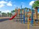 Community playground featuring a red slide, blue posts, and yellow accents near palm trees at 6231 Curlew Dr, Las Vegas, NV 89122