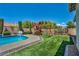 Backyard with pool, playset, artificial turf, and manicured landscaping at 6423 Grayback Dr, North Las Vegas, NV 89084