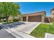 Spacious driveway leading to a two-car garage, complemented by lush green lawns and desert landscaping at 6423 Grayback Dr, North Las Vegas, NV 89084