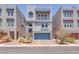 Modern, three-story home features a blue garage door and stylish architectural details at 8076 Haywood Estate Ave, Las Vegas, NV 89113